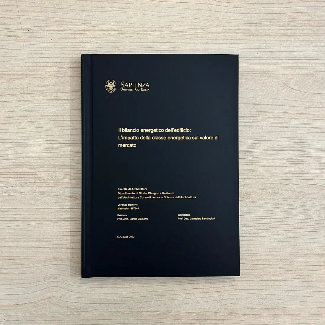 Tesi di laurea con copertina rigida nera e stampa foil oro, rilegata da GUUG per la Sapienza di Roma
